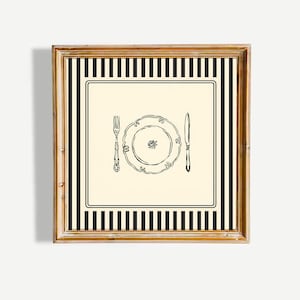 Może przedstawiać: Oprawiony wydruk z czarno-białą ilustracją nakrycia stołu. Ilustracja przedstawia talerz, widelec i nóż na kremowym tle, obramowane czarno-białymi paskami i złotą ramą.