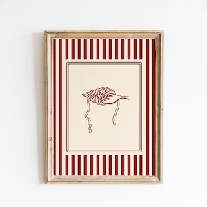 May include: Framed art print featuring a red and cream color scheme. The artwork depicts a hand holding a fork with spaghetti. The background has a cream color with a red border and red vertical stripes.