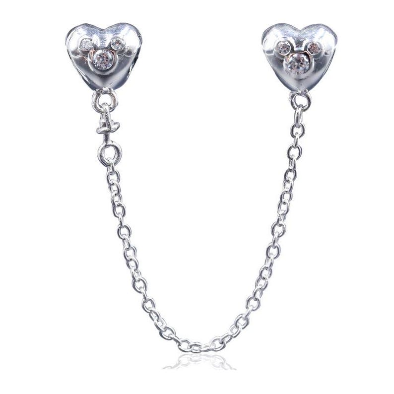 May include: Silver-toned earrings connected by a delicate chain. Each earring features a heart-shaped design with a Mickey Mouse-inspired motif and sparkling clear stones. The earrings are designed to be worn together.