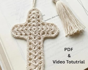 Peut inclure: Un marque-page en forme de croix crocheté en fil blanc cassé avec un motif ajouré complexe et un pompon assorti attaché au sommet. Le texte PDF & Video Toturial est imprimé en noir sur la surface près du bas à droite du marque-page.