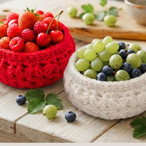 Peut inclure: Deux bols ronds crochet&eacute;s &agrave; la main avec un motif textur&eacute; en forme d'&eacute;toile. Un bol est rouge vif et rempli de fraises, framboises et cerises fra&icirc;ches. L'autre bol est blanc cass&eacute; et contient des raisins verts, des myrtilles et des groseilles.