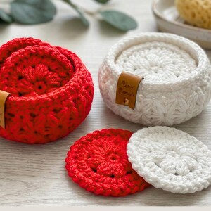 Peut inclure: Deux paniers ronds au crochet, l'un rouge vif et l'autre blanc, contenant chacun des dessous de verre circulaires assortis. Chaque panier comporte une petite &eacute;tiquette en cuir marron avec le texte Love Handmade et un rivet dor&eacute;.
