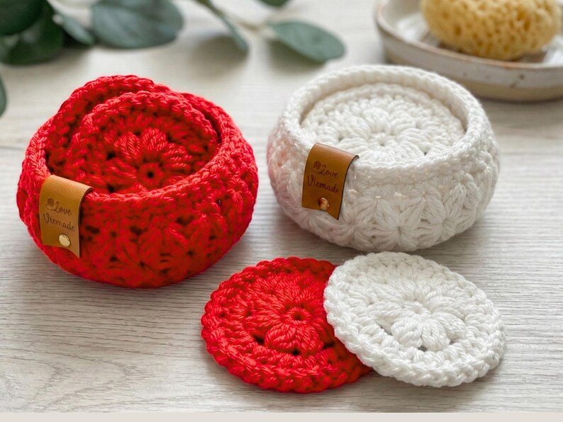 Peut inclure: Deux paniers ronds au crochet, l'un rouge vif et l'autre blanc, contenant chacun des dessous de verre circulaires assortis. Chaque panier comporte une petite &eacute;tiquette en cuir marron avec le texte Love Handmade et un rivet dor&eacute;.
