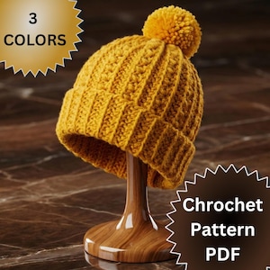 May include: A mustard yellow crochet beanie with a matching pom-pom, displayed on a wooden stand. The text "3 COLORS" is in a gold starburst. The text "Chrochet Pattern PDF" is in a brown starburst.