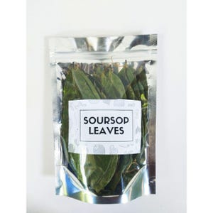 May include: A silver foil pouch containing green soursop leaves. The pouch has a white label with the text "SOURSOP LEAVES" in black. The background is a plain white surface.