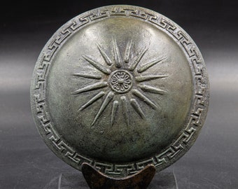 Antik grekisk bronssköld med grekisk nyckel och Verginas stjärna, symbol för Alexander den store, antikens grekiska imperiums krigssköld i metallskulptur