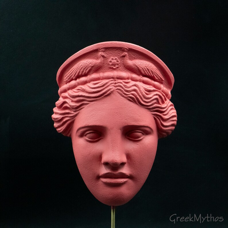 May include: A pink plaster bust of a woman with a crown of birds and a floral design. The bust is a replica of a classical Greek sculpture.