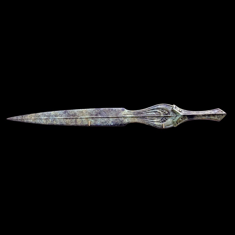 May include: An antique bronze dagger with a long, pointed blade and an ornate handle. The handle features a decorative design with curved lines and small circular accents. The dagger has a weathered appearance, suggesting age and use.