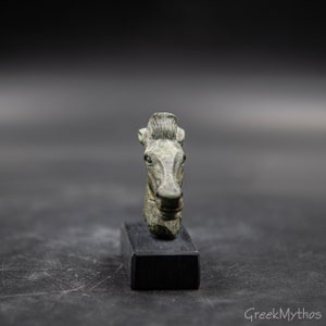 May include: A bronze horse head sculpture on a black stand. The sculpture is a detailed depiction of a horse's head with a mane and a bridle.