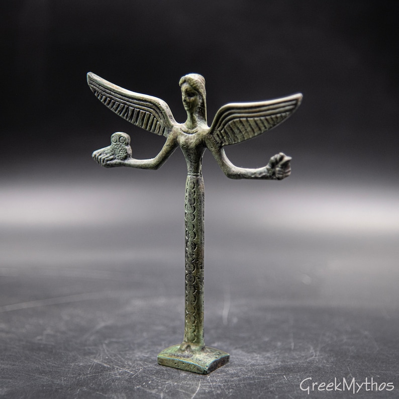 May include: A bronze statue of a winged figure with four arms. The figure is holding an owl in one hand and a flower in another. The statue is standing on a square base.