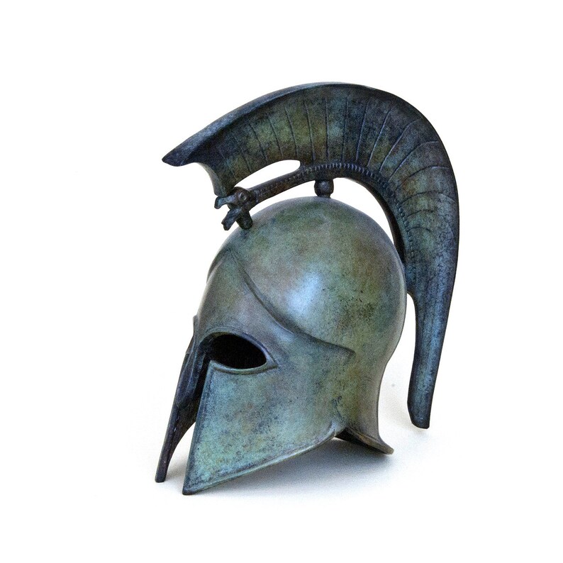 May include: A bronze Greek warrior helmet with a plume on top. The helmet is a replica of an ancient Greek helmet and is a popular decorative item.