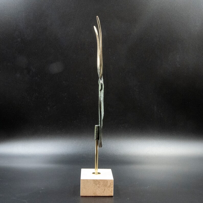 May include: A bronze sculpture of a stylised bird with long, thin wings. The sculpture is mounted on a small, square, beige marble base.