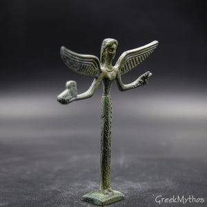 May include: A small bronze statue of a winged figure with outstretched arms. The figure is standing on a square base and has a detailed design.