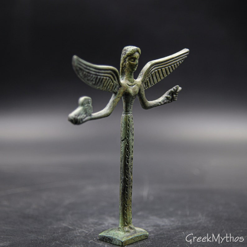 May include: A small bronze statue of a winged figure with outstretched arms. The figure is standing on a square base and has a detailed design.