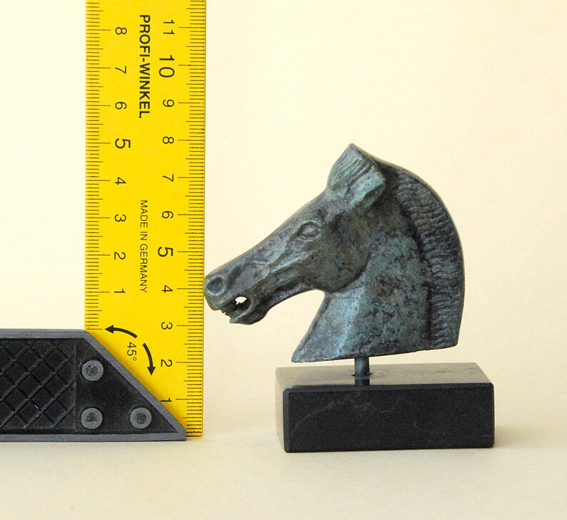 May include: A bronze horse head sculpture on a black marble base. The sculpture is about 5 inches tall and is a detailed representation of a horse's head.