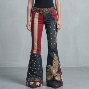 May include: Denim flare jeans with a patriotic design. The jeans feature red and white stripes on one leg, and a blue background with stars and an eagle graphic on the other. The words "We the People" are at the bottom.