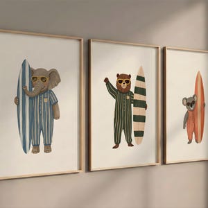 Puede incluir: Tres impresiones artísticas enmarcadas con animales antropomórficos con tablas de surf. Un elefante con pijama a rayas azules, un oso con pijama a rayas verdes y un koala con pijama a rayas naranjas, todos con gafas de sol.
