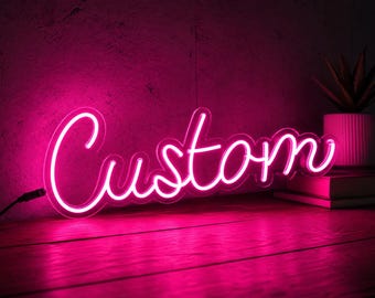 May include: A bright pink neon sign featuring the word Custom in a cursive script font. The sign is illuminated with a vibrant pink glow, casting light onto the surface below. A black power cord extends from the left side of the neon lettering.