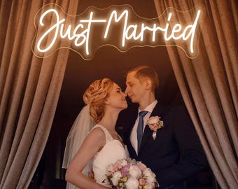 May include: A wedding scene featuring a couple embracing under a glowing neon sign that reads "Just Married." The bride wears a white dress and veil, holding a bouquet. The groom is in a dark suit with a blue tie. The background includes draped curtains.
