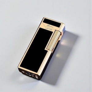 May include: A rectangular gold-toned lighter with a black central panel. The lighter has the word "Derui" and "Lighter" printed on it. The side features a decorative, textured design. The lighter is on a light grey surface.