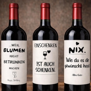 Könnte beinhalten: Drei Weinflaschen mit roten Verschlüssen und schwarzen Körpern. Jede Flasche hat ein weißes Etikett mit schwarzem Text. Die Etiketten enthalten Sätze wie "...WEIL BLUMEN NICHT BETRUNKEN MACHEN" und "NIX. Wie du es dir gewünscht hast".