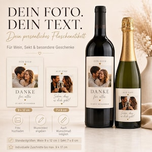 Può includere: Due bottiglie di vetro con etichette personalizzate che mostrano la foto di una coppia e del testo. L'etichetta del vino riporta 'FÜR DICH DANKE für alles DU BIST WUNDERBAR' e quella dello spumante 'AUF UNS! Schön, dass es dich gibt!'. Etichette di 9x12 cm e 7x8 cm.