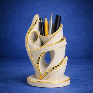 May include: A cream-colored pen holder with gold trim and blue and gold accents. The holder has a unique, curved design and holds several pens and pencils. The base is round and also trimmed in gold. The background is a solid blue.