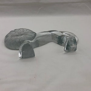 K&ouml;nnte beinhalten: Eine durchsichtige Glasfigur eines L&ouml;wen mit detaillierter M&auml;hne. Der L&ouml;we liegt mit dem Kopf zur Seite gedreht.