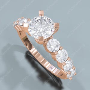 May include: Rose gold ring featuring a large, round, clear gemstone center stone, flanked by smaller, round gemstones. The band is rose gold with a series of smaller gemstones. The ring is marked with "14K".