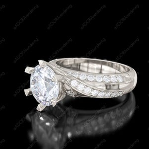 May include: A silver engagement ring with a large, round, clear gemstone as the centerpiece. The band features smaller, sparkling stones and a detailed, flowing design. The ring is set against a black background.