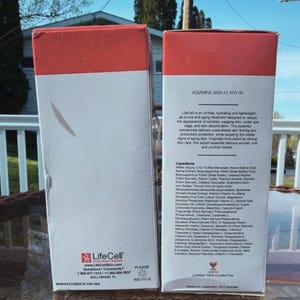 May include: Two white and red LifeCell skincare product boxes. The boxes have text that describes the product as an oil-free, hydrating, and lightweight anti-aging treatment. The boxes also list the ingredients and company information.