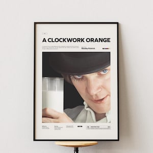 Op de afbeelding: Een ingelijste filmposter voor "A Clockwork Orange" met de titel van de film in witte letters. De afbeelding toont een close-up van een persoon met opvallende oogmake-up die een glas melk vasthoudt. De naam van de regisseur, Stanley Kubrick, is ook zichtbaar.