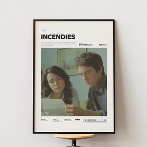 May include: A white ceramic mug with a black handle and the text "But First, Coffee" in a black, handwritten-style font. The mug is on a white surface.