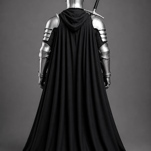 May include: A suit of silver metal plate armor featuring a rounded helmet, segmented shoulder and arm guards, and a long black hooded cloak. A long sword with a black hilt and silver crossguard is positioned diagonally across the back.