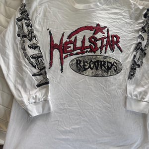 white Hellstar Records long sleeve t-shirt features a bold red and black graphic on the front and black skeleton graphics running down both