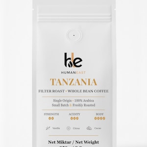 May include: White coffee bag with the text "HUMANEAST TANZANIA FILTER ROAST WHOLE BEAN COFFEE." The bag details the coffee's origin, roasting, and flavour notes. Net weight is 250 g.