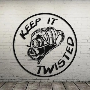 May include: Black metal wall art featuring a clenched fist inside a circle. The words "KEEP IT TWISTED" are written around the fist. The art is mounted on a white brick wall with a wooden floor.