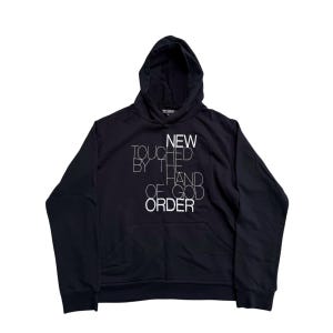 May include: Black hooded sweatshirt with a front pocket and white text that reads "NEW TOUCHED BY THE HAND OF GOD ORDER". The sweatshirt has a drawstring hood and long sleeves.