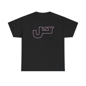 May include: Black t-shirt with the word "JOY" in a stylized, light pink font across the chest. The design features a unique, geometric font with rounded edges and a small circle above the "J". The shirt is made of a soft material.