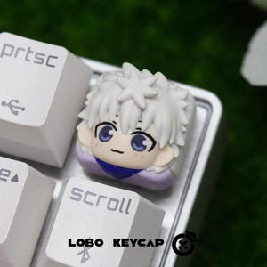 May include: A custom keycap featuring a white-haired anime character with blue eyes and a purple collar. The keycap is on a keyboard with the text "SCROLL" and "prtsc" visible. The brand "LOBO KEYCAP" is also displayed.