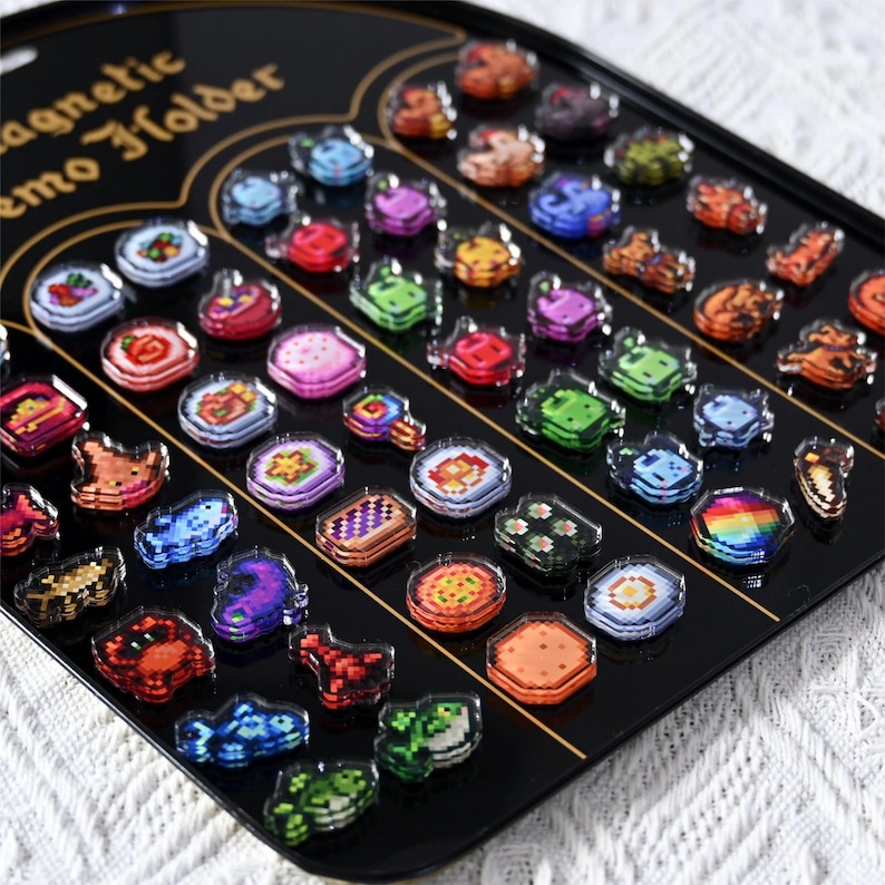 May include: A black magnetic memo holder filled with colourful pixelated magnets. The magnets feature various designs, including food items, geometric shapes, and abstract patterns. The text "magnetic memo holder" is visible on the holder.
