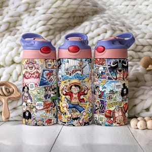 May include: Three water bottles with a pink base, blue lid, and red button. The bottles are covered in colorful comic book panels featuring characters and scenes. The background is a soft, white, textured surface.