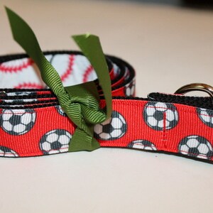 May include: Red and black soccer ball patterned belt with a green bow and silver buckle.