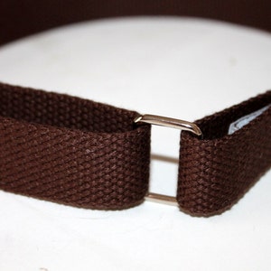 May include: A brown canvas belt with a silver metal buckle.