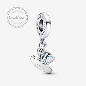 May include: A sterling silver charm featuring a teacup design with blue floral accents. The charm has the text "Cup of Tea Solves Everything" and is from DazzleVault. The charm is a jewelry item.