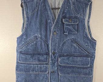 May include: A blue denim vest featuring a V-neckline, a button-front closure, and multiple utility pockets. The garment includes a chest pocket with a flap and two large lower pockets. A label at the inner neckline reads Polo Ralph Lauren.