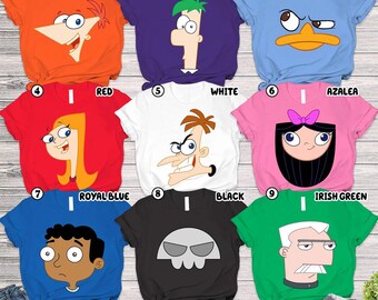 May include: Nine colorful t-shirts featuring cartoon character designs. The shirts are in various colors, including orange, purple, Carolina blue, red, white, azalea, royal blue, black, and Irish green. Each shirt has a different character graphic.