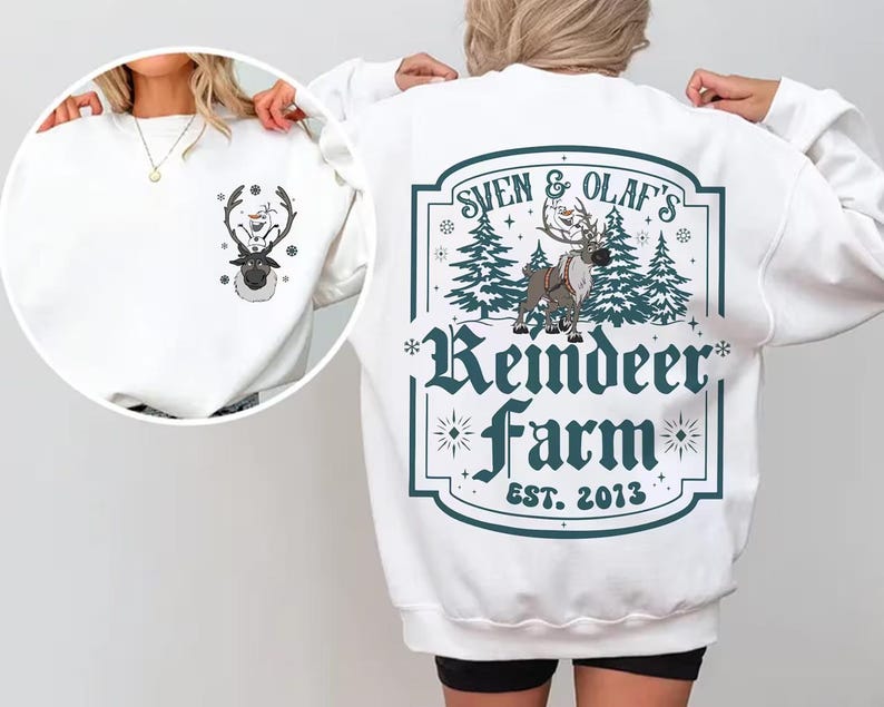 Pode incluir: Camisola branca com um desenho de rena e boneco de neve. A parte de tr&aacute;s apresenta um design turquesa e branco que diz "Sven & Olaf's Reindeer Farm EST. 2013". A frente tem um desenho menor da rena e do boneco de neve.