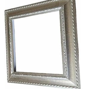 Peut inclure: Un cadre photo argenté avec une bordure décorative en forme de corde et des détails d'angle ornés. Le cadre a une ouverture carrée et est légèrement incliné, mettant en valeur sa surface texturée et son design.