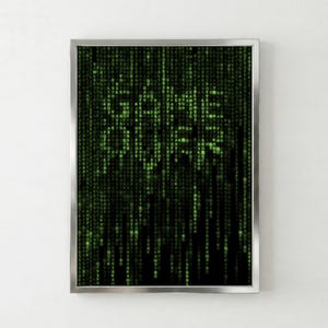 Könnte beinhalten: Gerahmter Druck mit digitalem Regen aus grünen Zeichen, mit dem Wort "CODE" prominent dargestellt. Das Kunstwerk hat einen schwarzen Hintergrund und einen silbernen Rahmen, wodurch eine moderne Ästhetik entsteht. Das Design erinnert an Computercode.